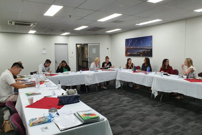 Instructor leading a mental health first aid training session with employees in a modern office setting